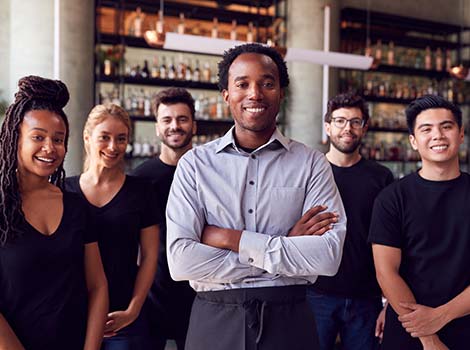 Group of smiling servers standing in front of bar